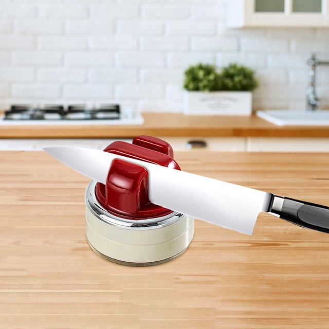Professional Kitchen Knife Sharpener Tool with Strong Suction Base, designed for efficient sharpening of knives and scissors. The compact red and white sharpener is displayed on a wooden countertop in a modern kitchen, ideal for home cooking enthusiasts and easy storage.