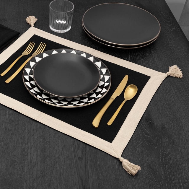 Thyme & Table Napperon, Noir et or avec un Centre Rectangulaire en Tissu Noir Bordé de Tissu beige et des Pompons à Chaque Coin, Ensemble sur une Table de Salle à Manger en Bois Foncé avec Couverts Dorés, Assiettes à Motif Géométrique Noir et Blanc et un Verre Transparent, Convient aux Repas Quotidiens Ou aux occasions Spéciales.
