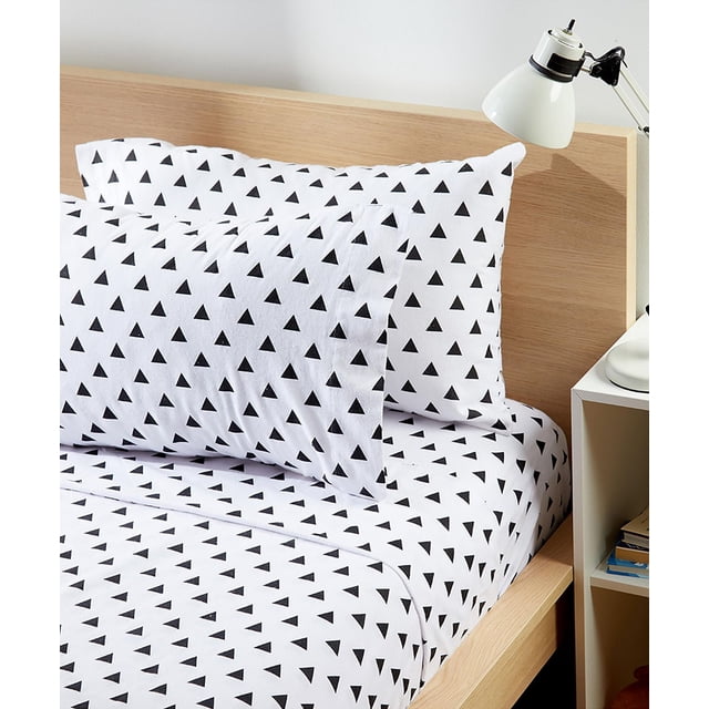 Johnson Home 200 TC Bed Sheet Set with printed cotton sheets in white featuring a black triangle pattern, including fitted and flat sheets plus matching pillowcases on a light wood bed frame beside a white desk lamp and a bedside shelf.