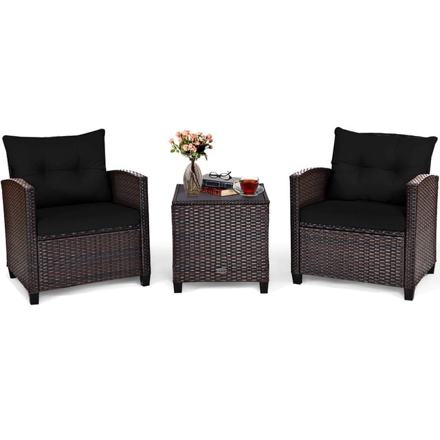 Giantex 3 Pieces Patio Furniture Set, a conversation set with two black cushioned rattan chairs and a matching rattan coffee table featuring a tempered glass top. The table is styled with a vase, books, and a cup, perfect for outdoor patio, garden, or balcony use.