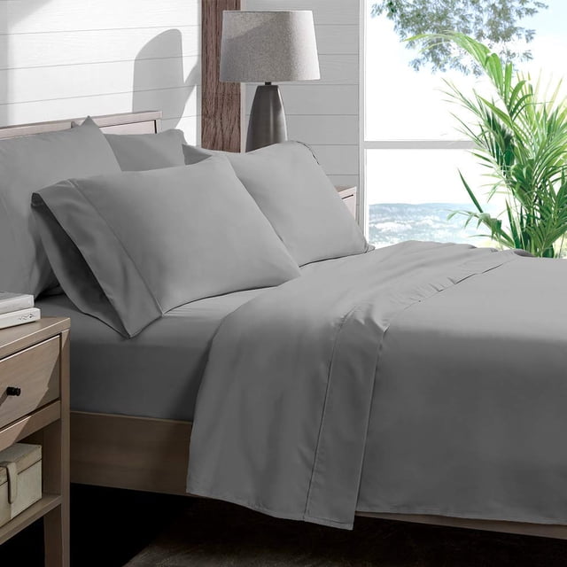 Sheet Set Silver Grey Solid 100 Percent Pure Cotton Super Soft 4-Piece Sheet Set with 12-inch pocket and 450 thread count, shown in a full-size bed setup. Includes fitted sheet, flat sheet, and two pillowcases in silver grey color. The bedding is displayed in a modern bedroom with a wooden nightstand, lamp, and a window overlooking greenery. Often used for gifting due to its luxurious feel and eco-friendly material.