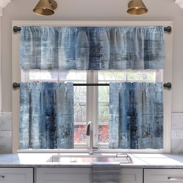 Blue blackout kitchen curtains tiers and valances set, featuring a modern abstract art design in shades of blue and grey. The set includes two tier panels and one valance, made of 100% polyester for a soft, fade-resistant finish. Displayed in a kitchen setting, the curtains are hung over a window with a view of a garden, providing privacy and light reduction while enhancing the decor.
