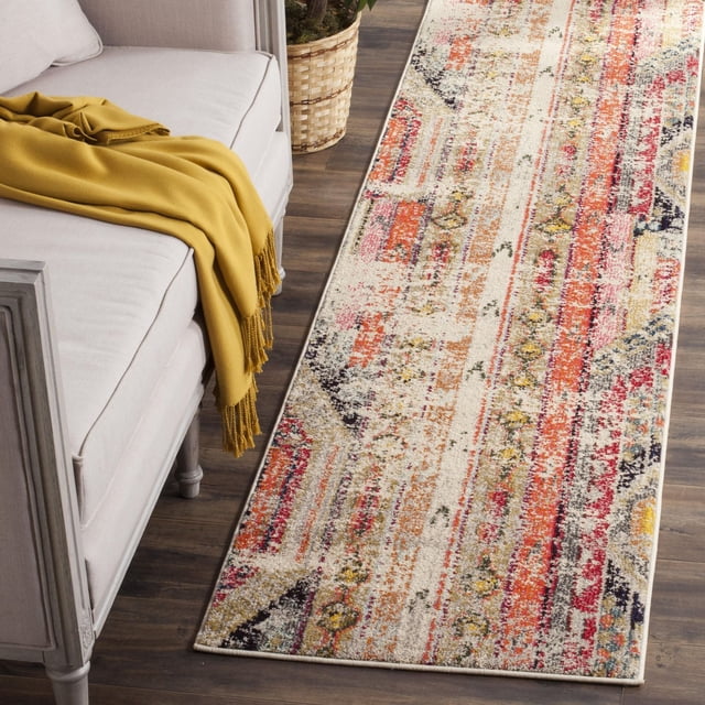 Safavieh Monaco Risto Abstract Area Rug runner with vibrant red, orange, yellow, and black abstract patterns on a cream background, power-loomed polypropylene with mixed loop pile, placed on dark hardwood floor beside a light grey sofa draped with a mustard yellow throw and a woven basket planter, suitable for adding Bohemian flair to hallways or entryways.