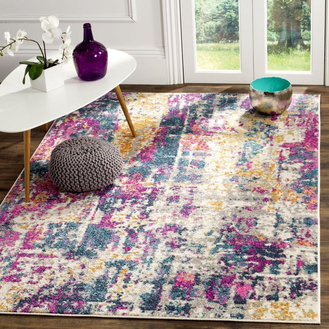 SAFAVIEH Madison Tapis Ivoire Abstrait Présentant un Motif Abstrait Multicolore dans des Tons Ivoire, Rose, Bleu et Jaune, Placé sur un Plancher de Bois Franc dans une Pièce Lumineuse. le Tapis Est Style avec une table Basse Moderne Blanche Tenant un vase en Verre Violet et une Orchidée Blanche, un pouf Tricoté Gris, et un Bol Métallique Martelé avec Intérieur turquoise Près des Portes en Verre Surplombant la Verdure. Utilisé Souvent pour Ajouter un accent Stylé aux Espaces de Vie Contemporains.