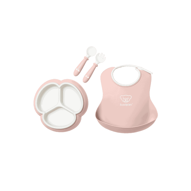 BabyBjorn Mealtime Set, 4 pcs, Powder Pink, a toddler feeding set including a trefoil-shaped plate with three compartments, a bib with adjustable neckband and spill pocket, and a spoon and fork with short, easy-grip handles. Made from BPA-free and PVC-free materials, dishwasher safe.