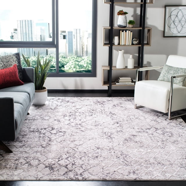 SAFAVIEH Amelia Roslyn Abstract Distressed Area Rug in a contemporary living room, featuring a large rectangular rug with plush synthetic yarn texture and abstract distressed pattern in soft neutral tones. It is placed between a gray sofa with a red pillow and a white armchair with a patterned cushion, near a black metal and wood shelving unit with books and decor, beside a window showing a city skyline and greenery. The rug is ideal for adding a modern, plush accent to living or family rooms.