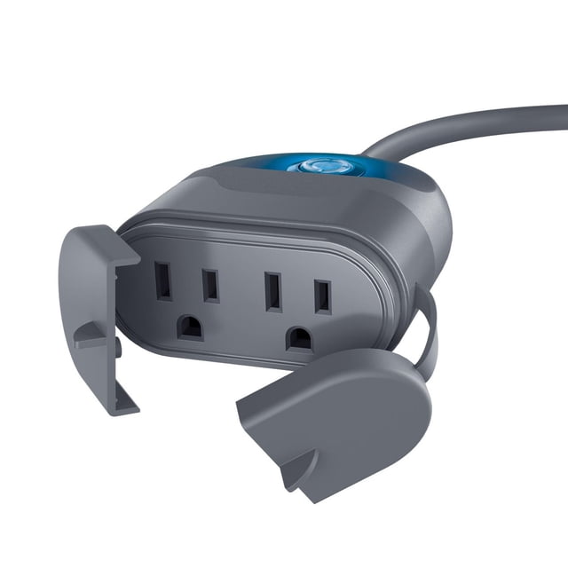 Merkury Smart Wi-Fi Indoor/Outdoor Plug in grey with two three-prong outlets protected by open weather-resistant covers, a blue power button on top, enabling remote scheduling and control of indoor or outdoor devices via app or voice without a hub.