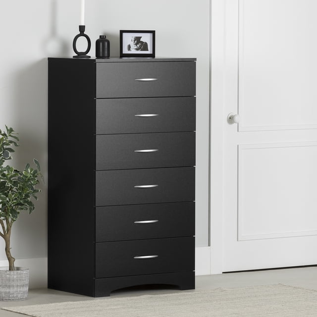 South Shore Step One Commode à 6 Tiroirs pour Adulte en Noir Pur avec six Tiroirs à Poignées en Métal et une base en Plaque à Pousser Courbée, Conçue pour le Rangement compact de Chambre, Présentée dans une Pièce Minimaliste à Côté d'Une Porte Blanche et d'Une Plante en Pot, Surmontée d'Un vase Noir, d'Un Porte-Bougie Circulaire et d'Une photo Encadrée, Convient pour Organiser des Vêtements Ou du Linge dans de Petits Espaces.