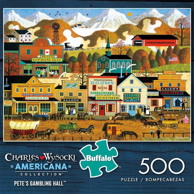 Buffalo Games - Americana Collection - Pete's Gambling Hall - 500 Piece Jigsaw Puzzle depicting a colorful vintage western town with detailed storefronts including Pete's Gambling Hall, hardware store, saloon, gunsmith, bakery, and land office, set against autumn trees and snow-capped mountains, featuring horse-drawn carriages and townspeople on a dirt road.