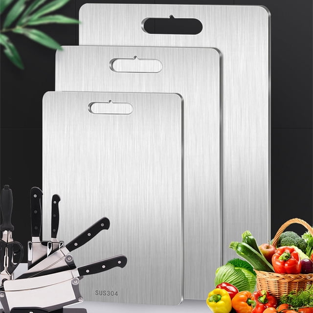 Vaidha Titanium Cutting Board - Stainless steel cutting board for kitchen made of 304 food-grade material. The image shows three cutting boards of varying sizes with a brushed silver finish, each featuring a handle cutout for easy hanging. The boards are displayed alongside a set of knives and a basket of fresh vegetables, emphasizing their versatility for cutting meat, fruits, and vegetables. Durable, dishwasher-safe, and resistant to scratches and dents.