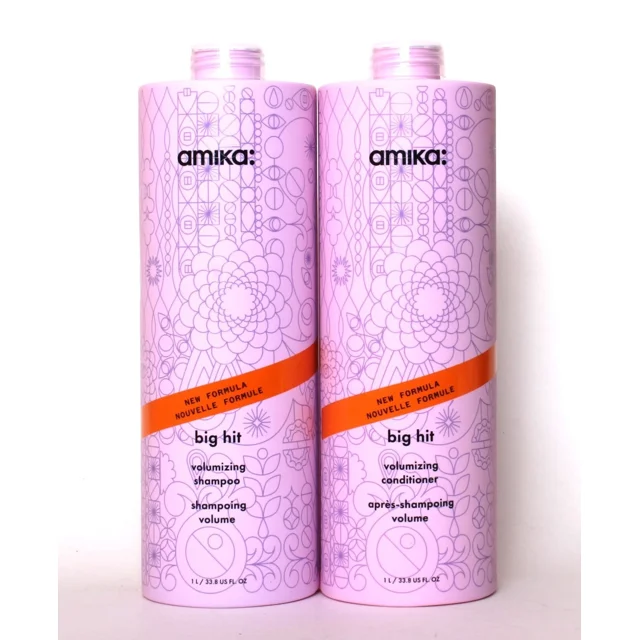 Amika Big Hit Volumizing Shampoo + Conditioner 1000mL Duo featuring two pastel purple bottles with floral patterns. Each 1L bottle is labeled 'Big Hit' with 'Volumizing Shampoo' or 'Volumizing Conditioner' and an orange band highlighting 'New Formula.'