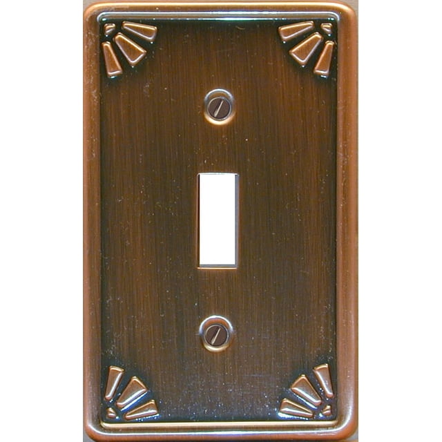 Atron Electro Industries Studio Bronze Toggle Wall Plate with a bronze metal finish and embossed decorative corner accents, featuring a central rectangular toggle switch opening and two mounting screws, ideal for home electrical switch upgrades.