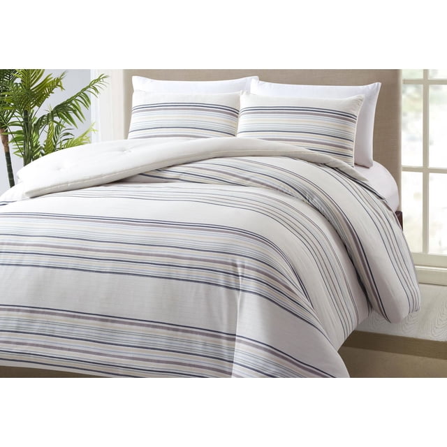 Better Homes & Gardens Comforter Set on a bed with beige upholstered headboard, featuring a breathable cotton comforter and matching pillow shams with envelope closures. The set has a striped pattern in neutral beige, gray, and blue tones, adding texture and softness to bedroom décor. The comforter is folded back slightly, and the shams are positioned upright. A green plant and window with white frame are in the background, enhancing the cozy bedroom setting.