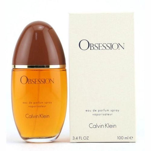 Obsession by Calvin Klein 100 mL eau de parfum spray with amber liquid in an oval glass bottle topped by a brown cap, displayed with its cream box labeled with brand and volume, featuring notes of mandarin orange, vanilla, lemon, basil, bergamot, and musk for daytime wear.