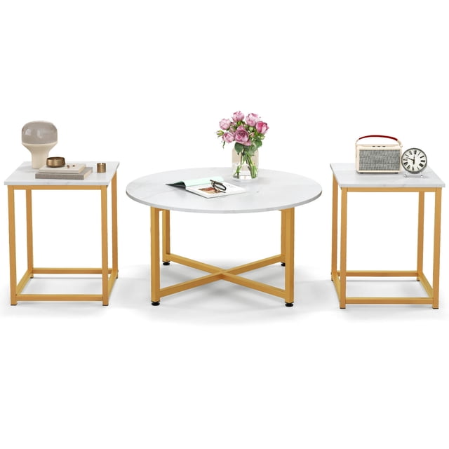 Costway Ensemble de 3 Pcs de tables Basses avec une Table Basse Ronde et Deux tables d'Appoint Carrées, Conçu pour le Mobilier de Salon. l'Ensemble Comprend des Plateaux en Bois d'Ingénierie Blancs et des Cadres en Métal Enduit de Poudre Dorée, avec une base en X sur la Table Basse et des bases Carrées sur les tables d'Appoint. des Patins de Pieds Ajustables Améliorent la Stabilité. des Articles Décoratifs comme des Fleurs, des Livres et une Horloge Sont Présentés sur les tables, Mettant en Valeur Leur design Moderne et Leur Fonctionnalité.