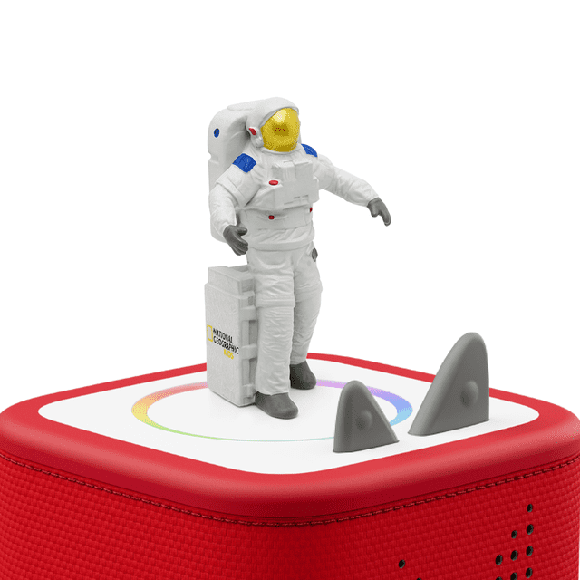 National Geographic Kids: Astronaut Tonie figurine in a white space suit with blue and red accents and a gold visor, standing on a red Toniebox educational audio speaker with textured fabric and control knobs, ideal for screen-free learning and storytelling.