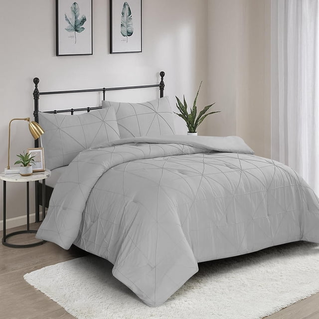 3 Pieces Hartford Pintuck Comforter Set in solid light grey with an all-over pintuck stitched pattern, including one comforter and two pillow shams on a black metal bed frame in a bedroom with light wood flooring, white rug, and green plants, suitable for easy machine care.