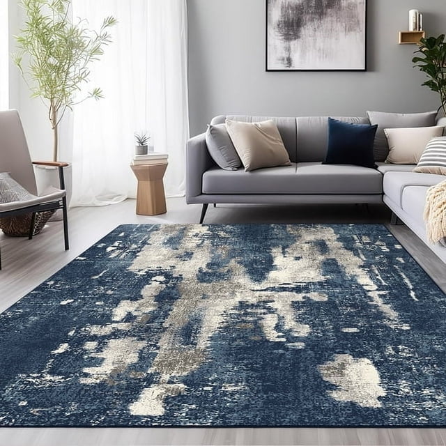 KUETH 8'x10' Area Rugs, Ultra Thin Non Slip Rug, Indoor Machine Washable Rugs for Living Room, Bedroom. This large area rug features a blue and gray abstract design with a low-profile, ultra-thin construction that fits seamlessly under furniture and doors. The rug is displayed in a modern living room setting with a grey sectional sofa, neutral cushions, and a light wood side table, complementing the decor. Its non-slip rubber backing ensures stability on hardwood or tile floors, making it ideal for high-traffic areas. Designed for durability and easy maintenance, this rug is machine washable and suitable for various spaces, including living rooms, bedrooms, and dining rooms.