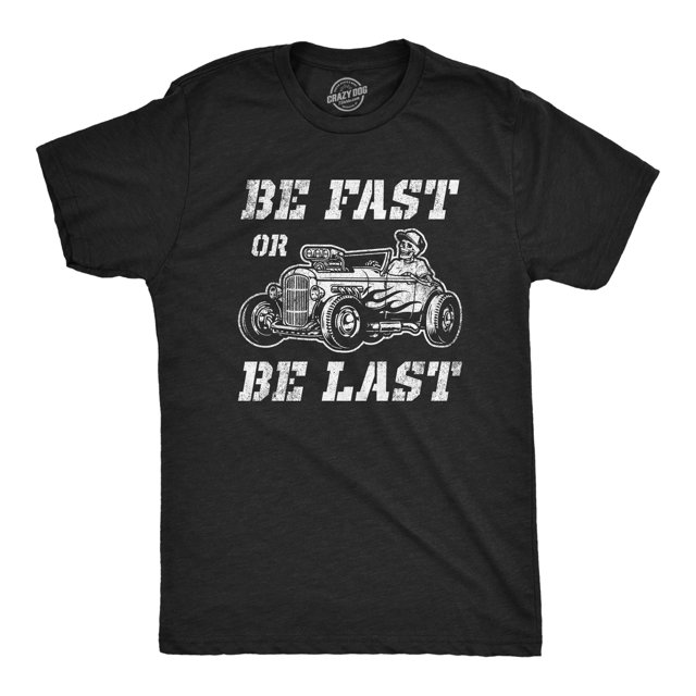 Mens Be Fast Or Be Last T Shirt Funny Hot Rod Racing Car Lover Graphic Novelty Tee for Guys in Heather Black, size L. Displays a bold white graphic of a vintage hot rod with flame decals and the text 'Be Fast Or Be Last' in distressed font. Crafted from super soft cotton with a slim fit design, perfect for casual wear, car enthusiasts, or graphic tee collectors.