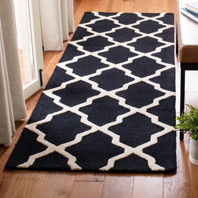Safavieh Cambridge Liam Geometric Area Rug runner with black background and white geometric trellis pattern, hand-tufted wool with plush cut and high/low loop pile textures, placed on hardwood floor near beige curtains and leather bench, ideal for adding modern American style to home or office.