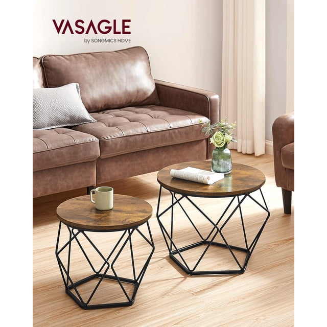 VASAGLE Small Coffee Table Set of 2, featuring a round rustic brown particleboard top and geometric ink black steel frames. Includes a large coffee table (19.7”Dia. x 15.7”H) and a smaller side table (15.7”Dia. x 14.2”H). Ideal for living rooms, bedrooms, or offices, shown in a cozy living room with a brown leather sofa and light wood flooring.