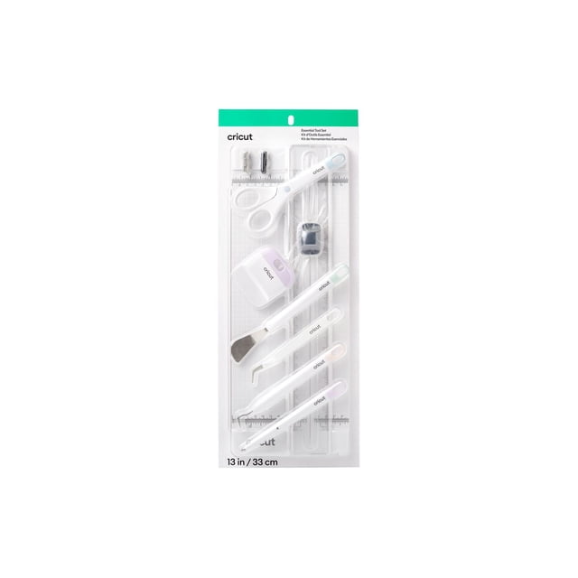 Cricut Essential tool Kit 13inch in clear packaging displaying seven white crafting tools including scissors, portable trimmer with replacement and scoring blades, scraper, tweezers, weeder, and scoring stylus, designed for precise cutting and scoring on vinyl, iron-on, paper, and Smart Materials.