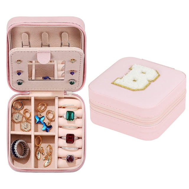 TopLLC 26 Letters Earring Jewelry Display Storage Box Case Organizer Flannel Tray Holder Gift in a compact square design. The box is shown in a soft pink color with a textured exterior and a decorative letter 'B' on the lid. The interior features multiple compartments, including ring slots, earring holders, and necklace hooks, all lined with a beige flannel material. A ribbon handle is attached for easy flipping of the earring panel. Ideal for storing rings, earrings, bracelets, and other small accessories. Dimensions are 10cm x 10cm x 5cm, and it is lightweight at 120g.