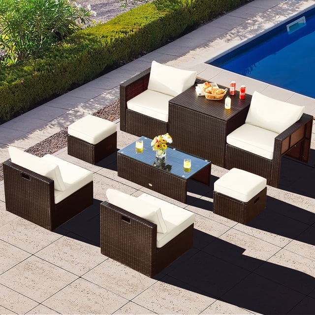 Gymax 8PCS Patio Rattan PE Wicker Conversation Set with mix brown rattan and off-white cushions. Includes 2 corner sofas, 2 armless sofas, 2 ottomans, a tempered glass coffee table, and a storage box. Modular design allows flexible arrangement, and the stackable set is ideal for compact storage. Made with all-weather materials for patios, gardens, or poolside use.