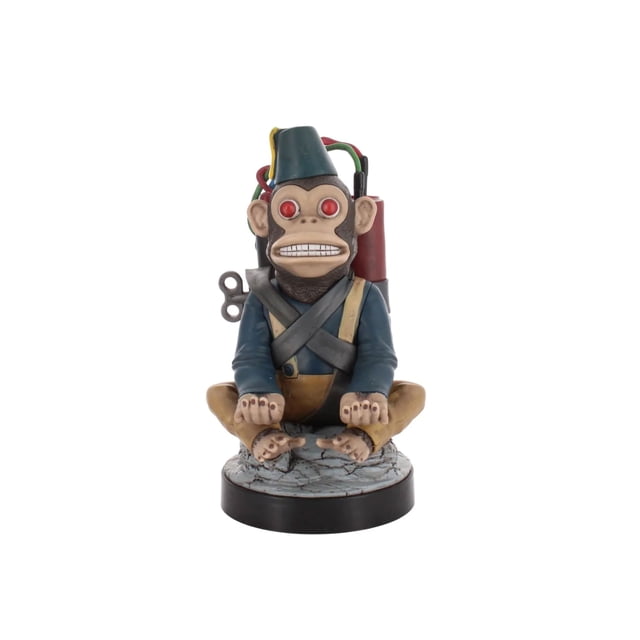 Exquisite Gaming Call of Duty: Monkey Bomb Cable Guy Original Controller and Phone Holder, an 8-inch tall front-facing figure of a monkey with red eyes wearing a blue jacket, tan pants, and blue fez hat, seated cross-legged on a cracked stone base with a wind-up key and colorful wires attached to a red bomb device, designed to hold gaming controllers, smartphones, or TV remotes.