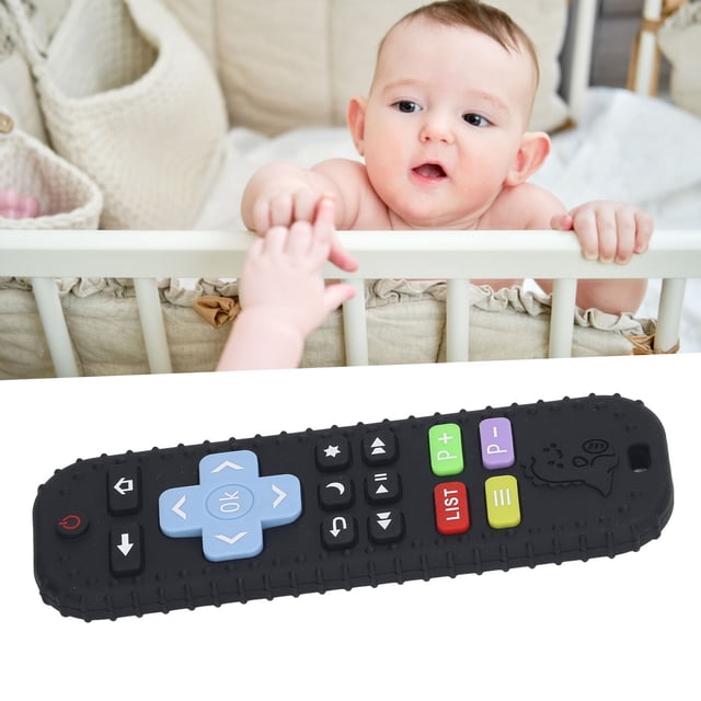Cartoon Remote Baby Toy, a silicone TV remote control-shaped infant chew toy for boys and girls. The toy mimics a real remote control with a black body and colourful buttons, including blue directional keys and green, red, and purple function buttons. Designed to promote sensory development and tactile exploration in babies. The background features a baby in a crib, highlighting its suitability for infants.