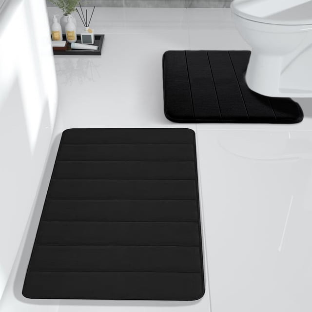 Xihbxyly Bathroom Rugs Sets 2 Piece in dark grey, featuring a memory foam bath mat and toilet mat. Made of velvet fleece with a rubber non-slip backing, these rugs are designed for quick drying and water absorption. The set includes a 24x16 inch bath mat and a 20x16 inch toilet mat, suitable for small bathroom spaces. Displayed in a modern bathroom setting with white tiles and minimal decor.