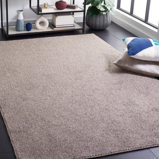 SAFAVIEH Lotus Leila Solid Area Rug in warm earthy beige with a texture-rich loop pile, displayed on dark flooring near decorative pillows and a black metal shelf with vases and books, suitable as a durable accent rug for casual décor.