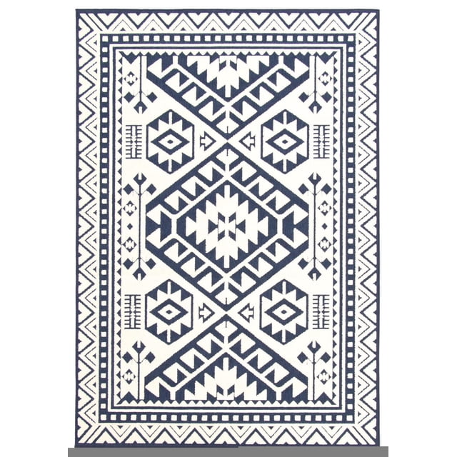 ECARPET Indoor/Outdoor for Balcony, Patio and Garden Aaya Blue Rug with a front-facing rectangular design featuring a navy blue and white geometric tribal pattern with diamond and arrow motifs. It has a high-low 3D effect and multiple borders including a zigzag outer edge. Suitable for indoor and outdoor use on patios, balconies, and gardens, it complements mid-century modern and urban loft styles and is fade and pet resistant.
