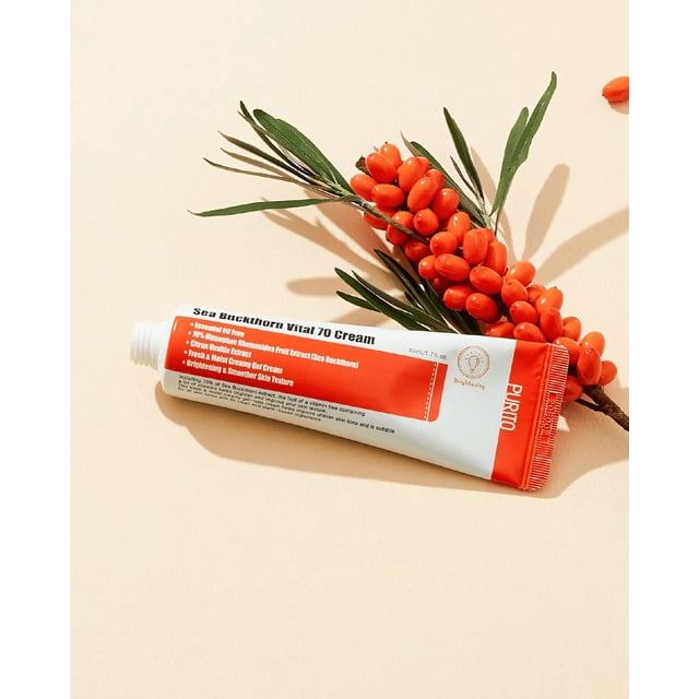 PURITO Sea Buckthorn Vital 70 Cream in a 50ml tube, featuring a white and orange design with product details printed on the packaging. The cream contains 70% sea buckthorn fruit extract, niacinamide, and other vegan-friendly ingredients to brighten and smooth skin. The tube is displayed alongside fresh sea buckthorn berries and green leaves on a light beige background.