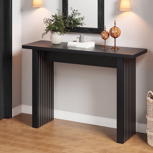 Wirrytor Table Console Carrée Noire de 43 Pouces pour Entrée, Présentant une Finition Noire Élégante avec des accents Verticaux Dorés sur les Pattes. Cette Table Polyvalente Est Fabriquée en MDF durable avec une Finition Façon Bois, Offrant une Esthétique Rustique Mais Moderne. Elle Est Stylée dans une Entrée Bien Éclairée avec des Articles Décoratifs, Y Compris un vase, des Livres et des Ornements Métalliques, Mettant en Valeur Sa Fonctionnalité comme Table d'Entrée Ou de sofa. la Table Comprend des Patins Discrets pour la Stabilité et Convient à une Utilisation dans les Salons, les Couloirs Ou les Aires de Repas