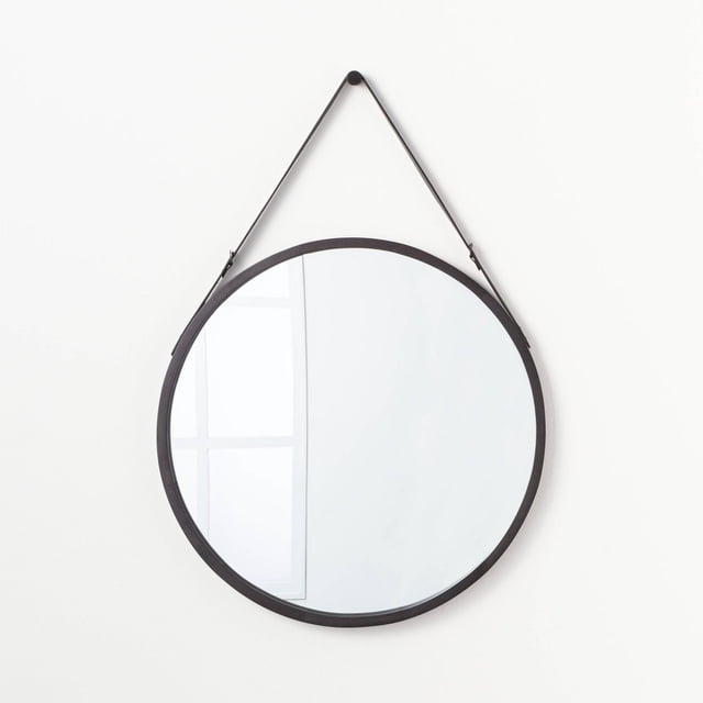 26-inch decorative wall mirror with a black wood frame and pleather strap hanger, designed by Threshold with Studio McGee. The round mirror features a minimalist black finish and a functional strap for easy wall mounting, ideal for entryways, living rooms, or bedrooms.