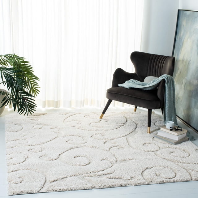 SAFAVIEH Florida Tapis Shag à Motif de Vignes Florales Douglas pour Aire de Vie dans une Pièce Lumineuse avec Rideaux Transparents, Présentant une Peluche Ton crème Ton sur Ton à Ourlet Haut-Bas avec Motifs de Vignes Damassées, Assorti à un Fauteuil Moderne Foncé avec Pattes à Bout Doré et un Jeté Bleu, à Côté d'Une pile de Livres avec une Tasse et des Lunettes.