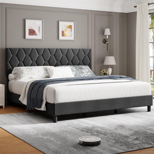 Yiwa Queen Size Platform Bed Frame with Upholstered Headboard and Wooden Slats Support, shown in a modern bedroom setting. The bed features a diamond block-patterned, foam-padded upholstered headboard in a dark grey tone, paired with a sturdy metal frame and thick wooden slats for noise-free support. Designed to hold up to 800 lbs, it includes 9 support legs and scratch-resistant feet. The adjustable headboard accommodates mattresses 11-15 inches thick, eliminating the need for a box spring. The bed is styled with white bedding, decorative pillows, and a blue throw blanket, placed on a grey area rug in a well-lit room with neutral walls and framed artwork.