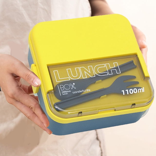 TIMIFIS Lunch Boxes Sealed Compartment Plastic Lunch Box with a yellow lid and blue base, held in hand. The lid features a transparent section with integrated cutlery storage containing a fork and spoon. This 1100ml adult lunch box is leak-proof, microwave-safe, dishwasher-safe, and ideal for office workers or kitchen essentials.