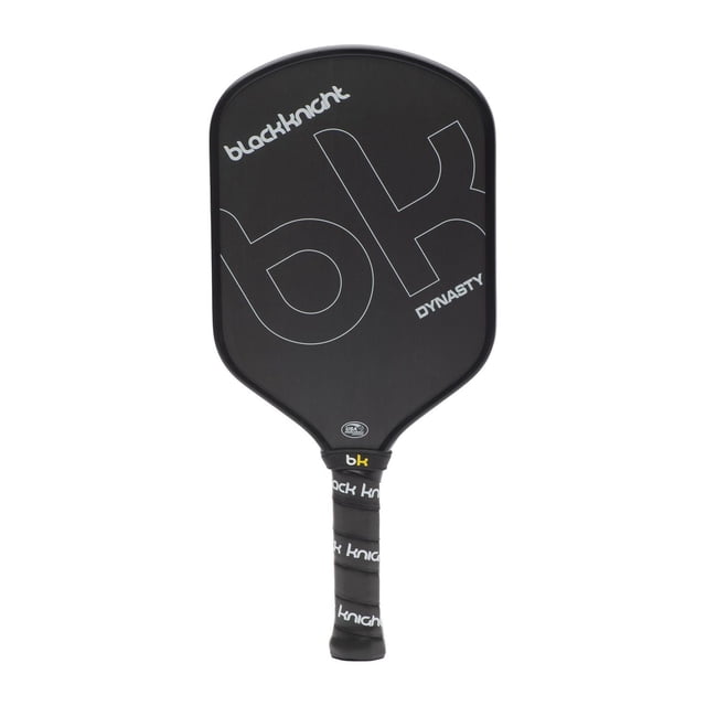 Black Knight Dynasty Pickleball Paddle with an elongated shape, raw carbon face, polymer honeycomb core, and midweight 8.01 oz design, measuring 16.5 by 7.5 inches, featuring a black matte finish with white 'bk' and 'Black Knight' logos, and a 4.125-inch circumference grip wrapped in branded black tape, engineered for power, spin control, and extended reach in pickleball play.
