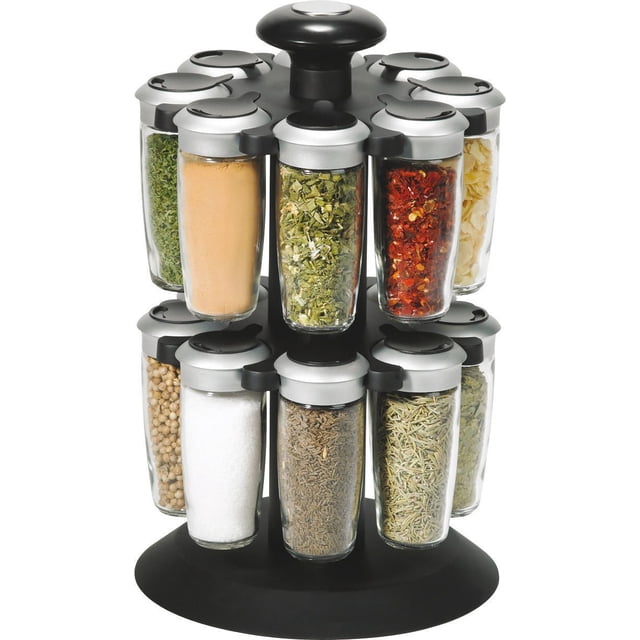 Trudeau Axia 16-Bottle Spice Carousel with a black revolving stand holding 16 clear glass jars with silver lids filled with various dried herbs and spices including chili flakes, rosemary, sea salt, coriander, and parsley, designed for compact kitchen organization and easy access, also suitable for organizing small craft supplies.