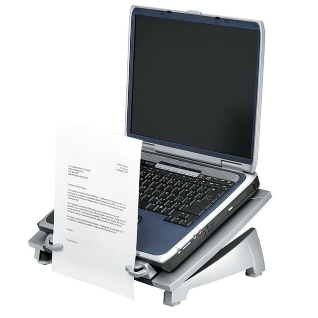 Fellowes® Office Suites Laptop Riser Plus shown holding a laptop with a black keyboard and dark blue palm rest on a silver adjustable stand. The riser features a stabilizing front edge with an in-line document holder holding a white sheet of paper, cooling vents to dissipate heat, and swivel feet for 360° rotation and cord access. Supports laptops up to 17 inches or 10 lbs, designed to raise the laptop to eye level for ergonomic comfort and productivity.