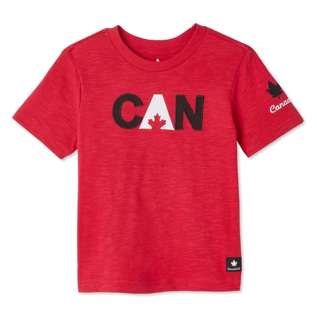 Canadiana Toddlers' Gender Inclusive Graphic Tee in red jersey knit with crew neckline and short sleeves, featuring black and white 'CAN' letters with a maple leaf on the front, a black maple leaf and 'Canada' text on the right sleeve, and a small black Canadiana logo tag at the straight hem, ideal for everyday comfort and pairing with joggers or jeans.