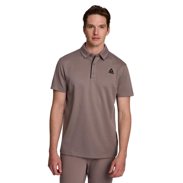 Reebok Men's Ace Performance Polo Shirt in muted taupe, crafted from 100% poly double side jacquard fabric, featuring short sleeves, a half-button collar, and the black Reebok Delta logo on the chest, worn with matching taupe pants on a white background, ideal for casual or semi-formal occasions.