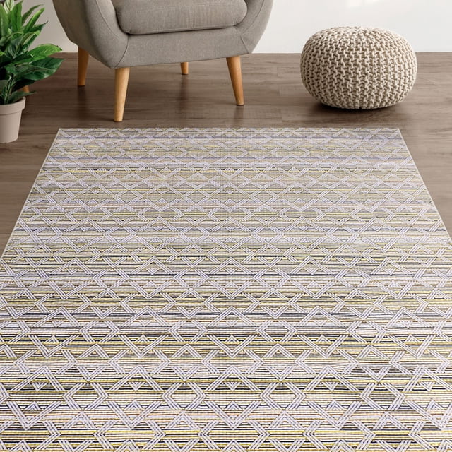 Mainstays Washable Audrey Westip Cream Printed Rug 4'x6' featuring a low-pile geometric diamond pattern in cream and muted gold microfiber, set on a wood floor near a grey armchair with wooden legs, a knitted cream pouf, and a green potted plant, suitable for living rooms, hallways, or entryways and easy to machine wash and store.