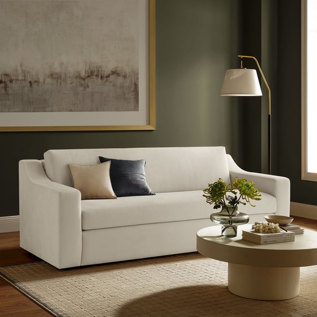 Modway Liora Performance Velvet Sofa in Alabaster, an 87-inch three-seater couch with a low-profile design, sloped track arms, and recessed legs for a sleek, floating appearance. Upholstered in stain-resistant performance velvet, this sofa features dense foam padding, pocket spring support, and zigzag coils for soft yet supportive seating. Displayed in a modern living room with a dark green wall, a large abstract painting, and a round coffee table with decor items. Dimensions: 87"W x 37.8"D x 32.7"H.