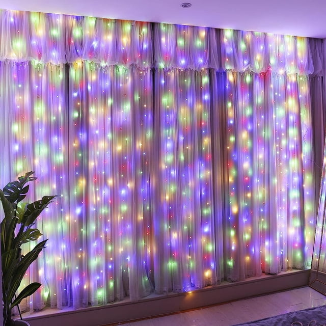Innotech 300LED multi-color fairy curtain string lights displayed on sheer curtains, creating a vibrant and festive ambiance. These USB plug-in lights offer 8 modes and remote control for customizable settings. Ideal for indoor and outdoor use, weddings, parties, and decorations. Includes hooks for easy hanging and adjustable S-shaped drooping design.
