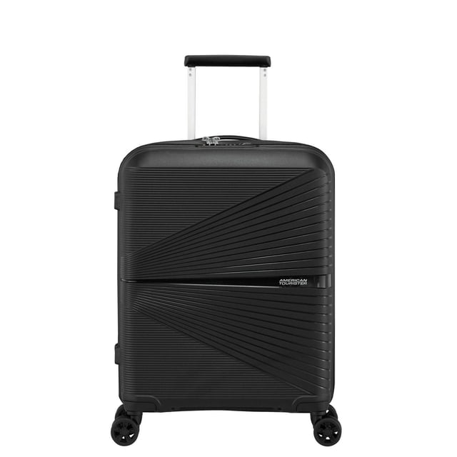 American Tourister Airconic Spinner Luggage in black, front view of a lightweight hard-shell carry-on suitcase with diagonal textured ridges, extended telescoping handle, four dual spinner wheels, and the American Tourister logo. Suitable for overhead compartments and ideal for organized packing on short trips.