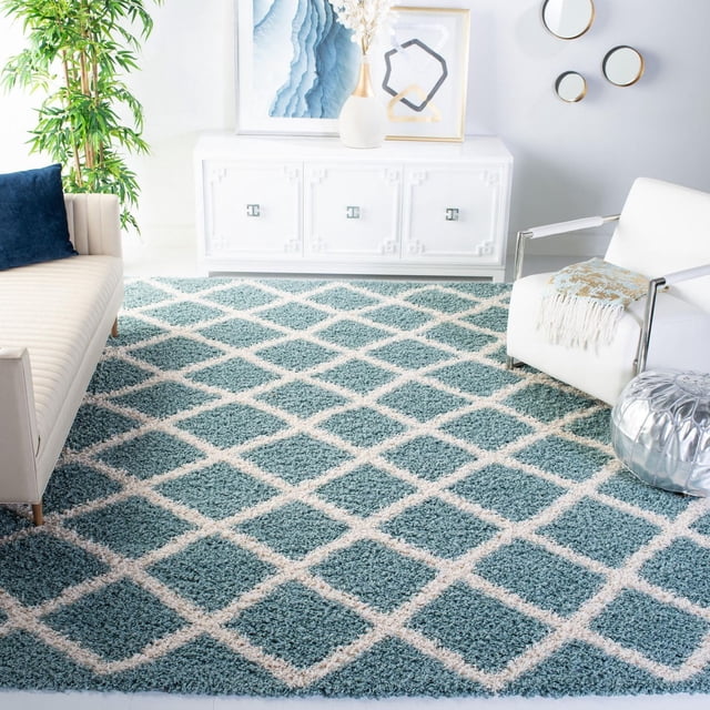 Safavieh Layla Geometric Plush Shag Area Rug featuring a blue and white diamond pattern with a plush texture, displayed in a bright living room with a cream sofa, navy pillow, white armchair with a throw, and white sideboard with decorative vases and abstract art. The durable synthetic fiber rug is suitable for high-traffic areas and adds texture and dimension to contemporary spaces.