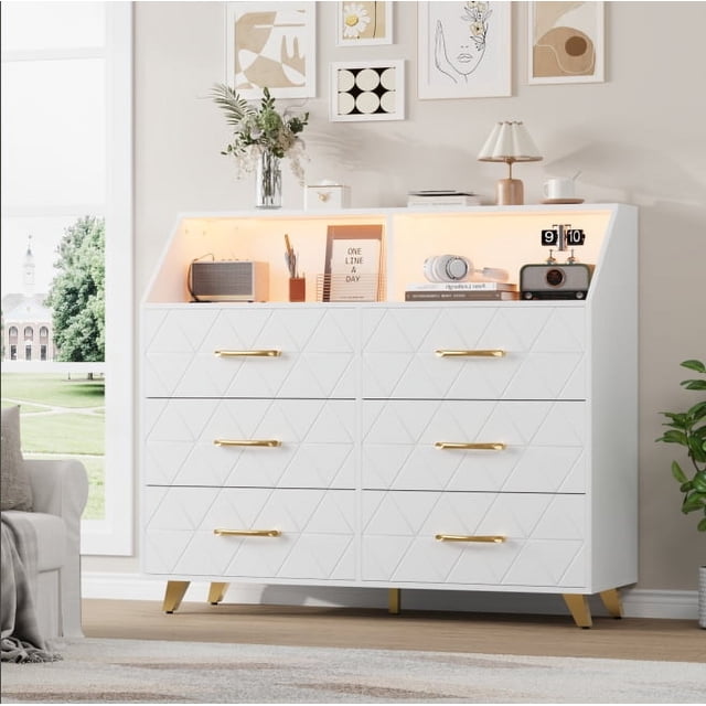 Commode à 6 Tiroirs avec Station de Recharge et Tablette de Rangement, Conçue comme une Armoire d'Entrée Moderne avec une Finition Blanche et un Motif Géométrique Triangulaire sur les Façades de Tiroirs. Poignées Dorées et Cinq Pieds Métalliques Robustes Renforcent Son Élégance et Sa Stabilité. Dotée d'Un Éclairage DEL, de Deux Prises CA et de Deux ports USB pour le Chargement d'Appareils. Six Tiroirs Spacieux Offrent un Grand Rangement, pendant Que l'Étroite Tablette Supérieure Expose des Articles de Déco. Convient aux Entrées, Chambres Ou Salons.